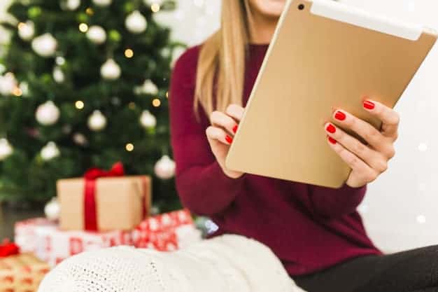 Femme avec une tablette devant son sapin de Noël